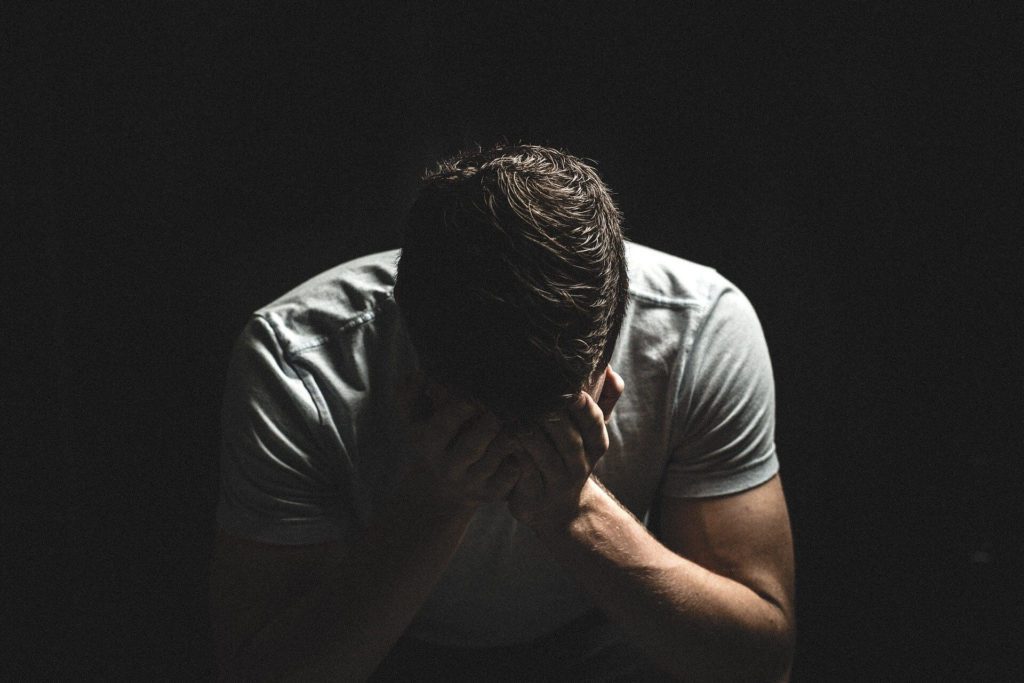 Young man holding his head in his hands.